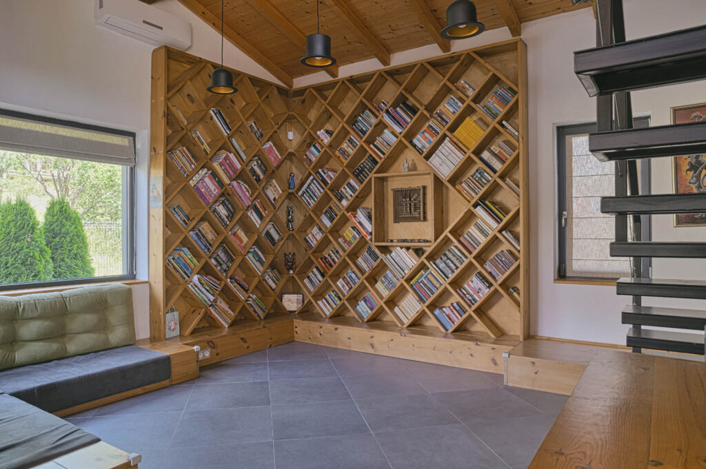 Модерна стая от Интериорен дизайн Studio28a с диагонална етажерка, диван и стълбище вдясно.