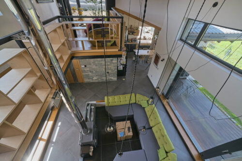 Модерно жилищно пространство с отворен план от Интериорен дизайн Studio28a, включващо секционен диван, таванско помещение и метални подпорни стълбове.