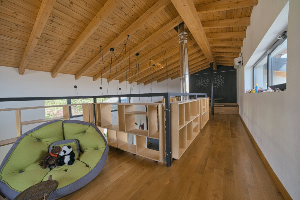 Таванско помещение с дървен таван, отворени рафтове, фотьойл с плюшени животни от Интериорен дизайн Studio28a.