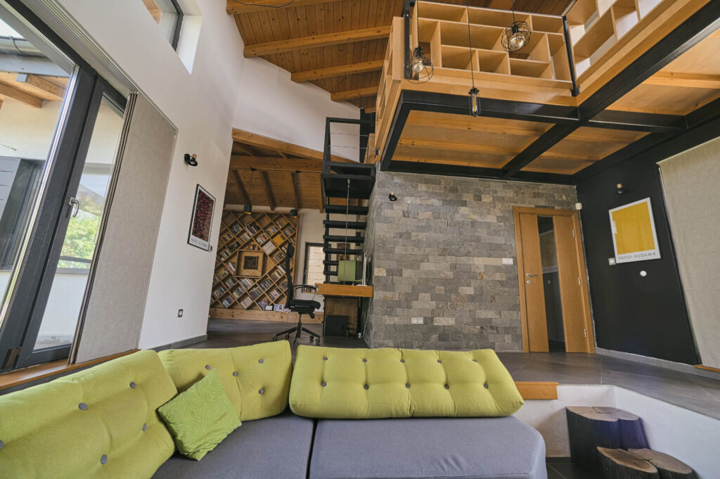 Модерна дневна от Интериорен дизайн Studio28a със зелен диван, дървен таван, каменна стена и метално стълбище.