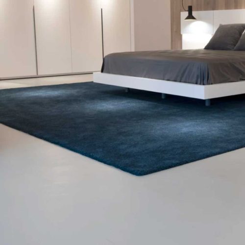 Модерна спалня от Интериорен дизайн Studio28a със син килим, бяло легло с платформа, сиво спално бельо и минималистичен декор.