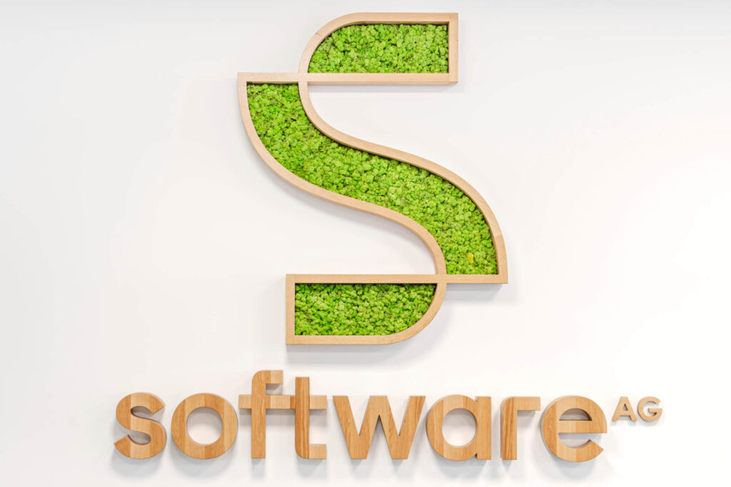 Голяма дървена буква "S" със зелен мъх над "software AG" от Интериорен дизайн Studio28a на бяла стена.