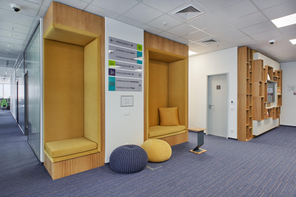 Модерен офис коридор с жълти кътове за сядане, пуфове и табели от Интериорен дизайн Studio28a.