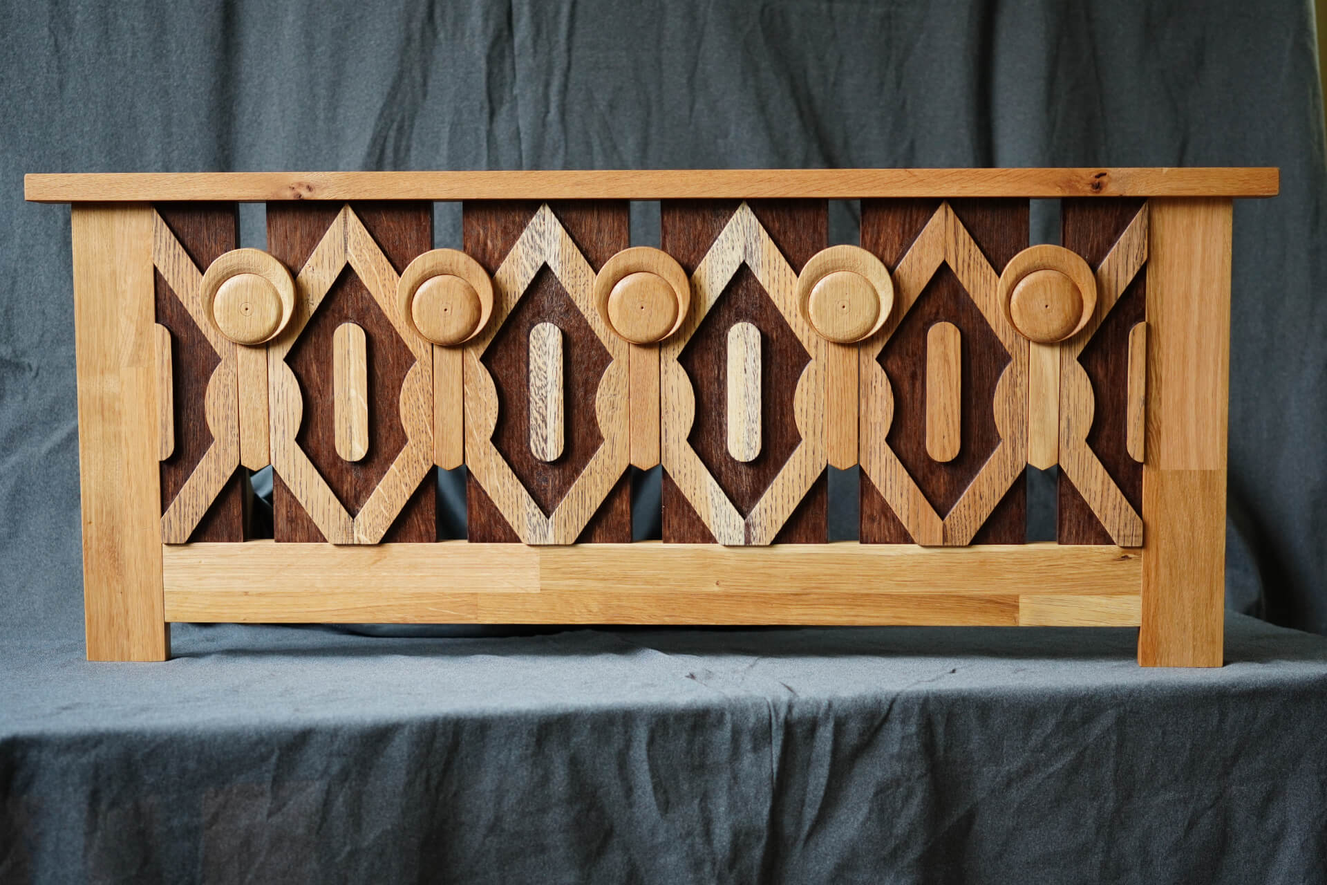 Дървена пейка с геометрична облегалка от Интериорен дизайн Studio28a с контрастни дървесни шарки.