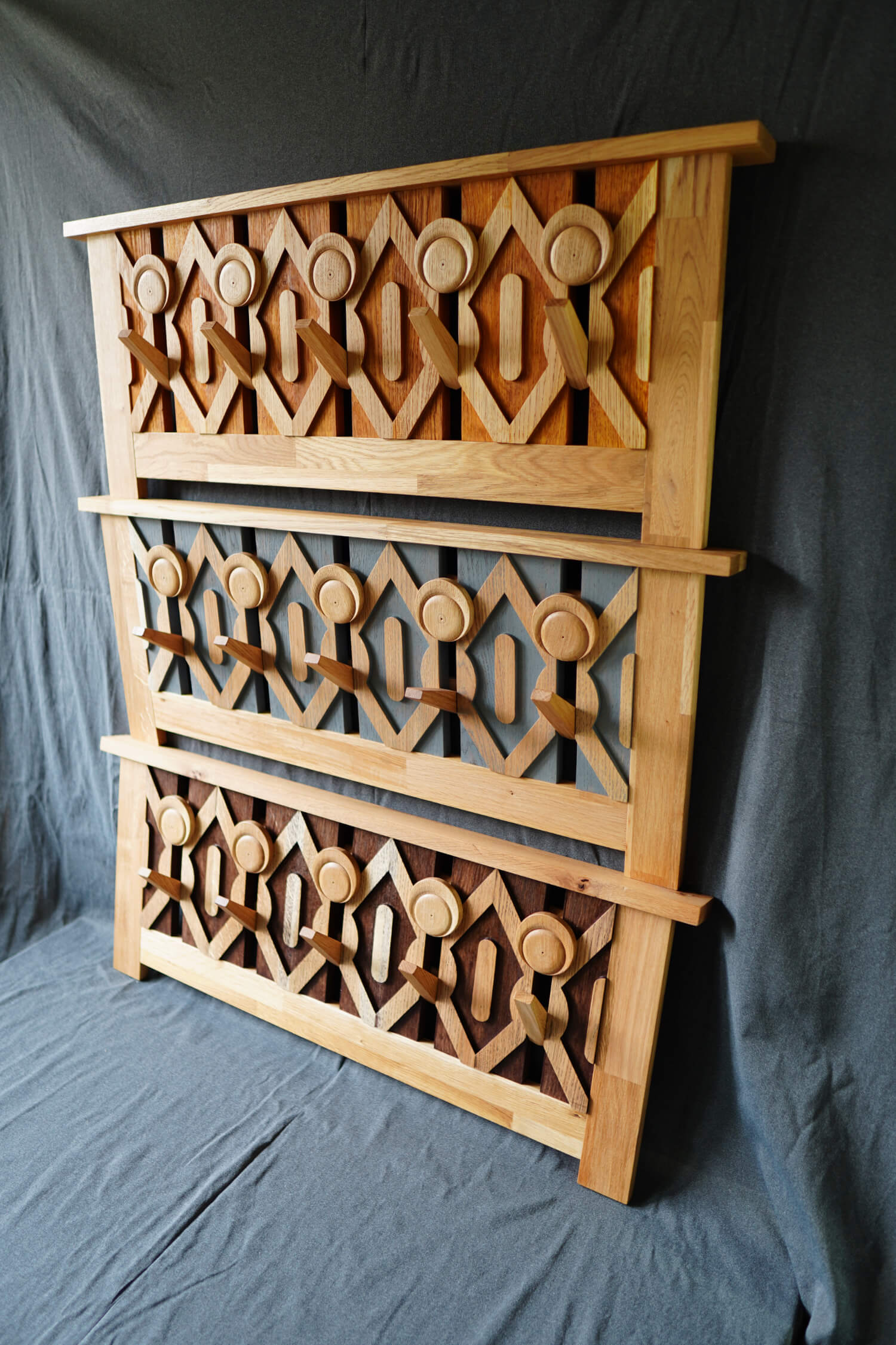 Три дървени панела с геометрични резби, представени от Интериорен дизайн Studio28a на фона на сив плат.