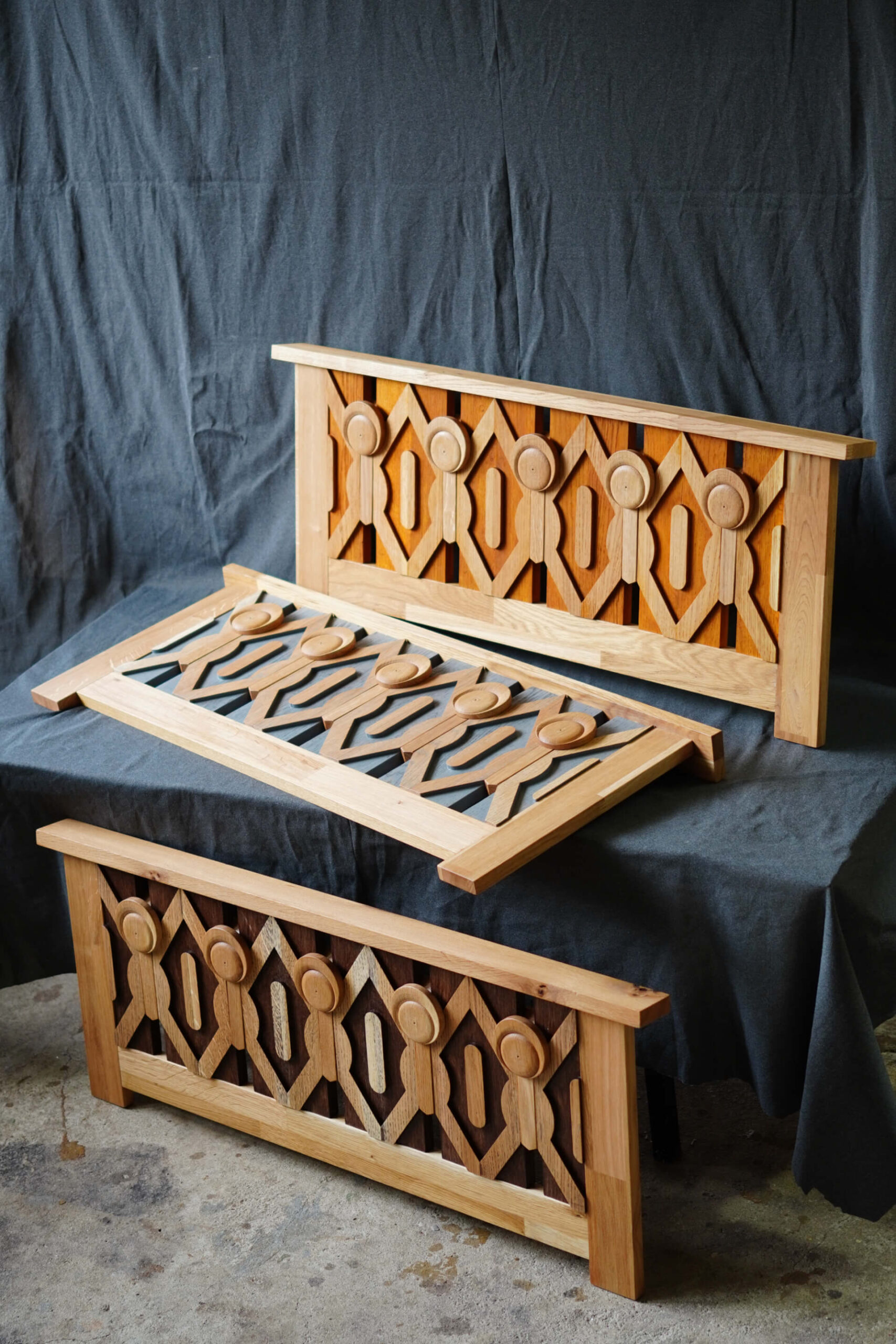 Три дървени панела с геометрични изрезки от Интериорен дизайн Studio28a са изложени на тъмен текстилен фон.