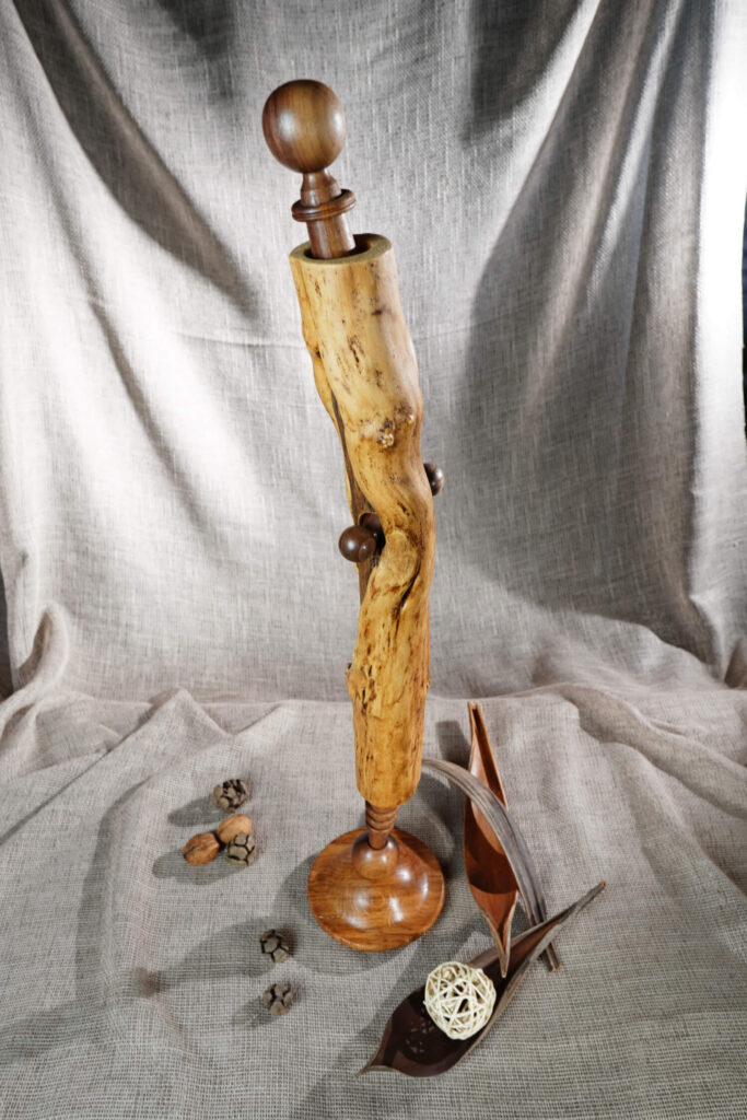 Висока дървена творба от Интериорен дизайн Studio28a стои върху плат с малки дървени акценти до нея.