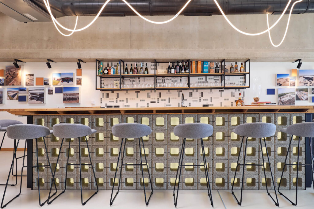 Модерен бар с високи табуретки, геометрични плочки и рафтове, създаден от Интериорен дизайн Studio28a.