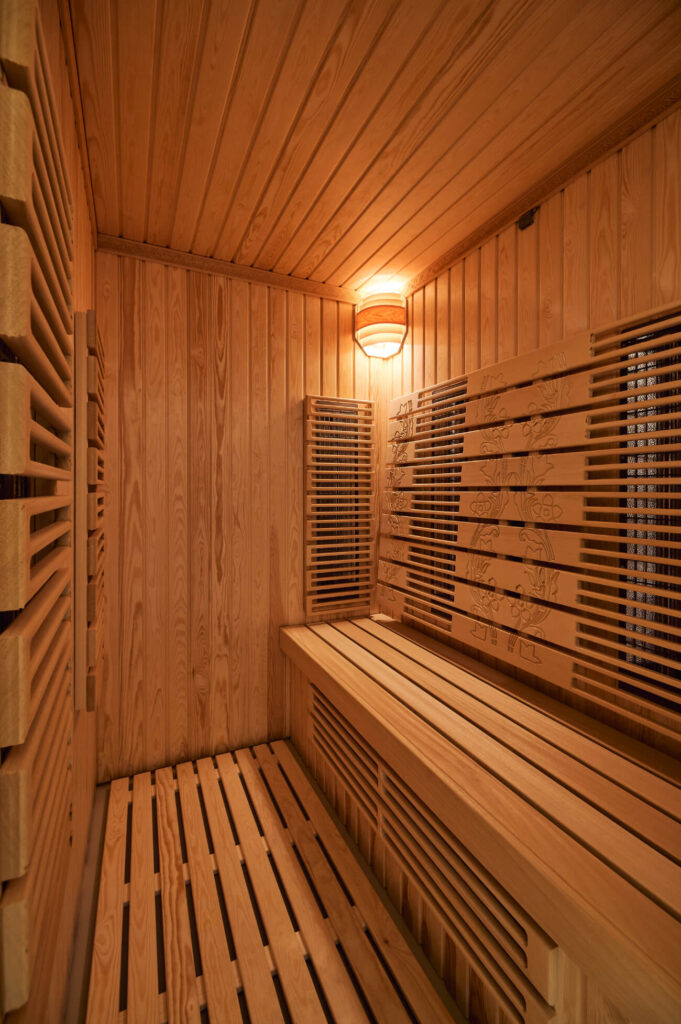 Дървена стая за сауна с пейки, решетъчни стени и осветително тяло на тавана от Интериорен дизайн Studio28a.