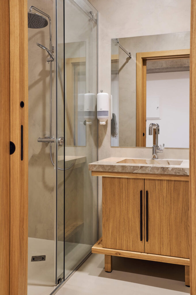 Модерна баня от Интериорен дизайн Studio28a със стъклен душ, дървена тоалетна чиния и монтиран на стената дозатор за сапун.