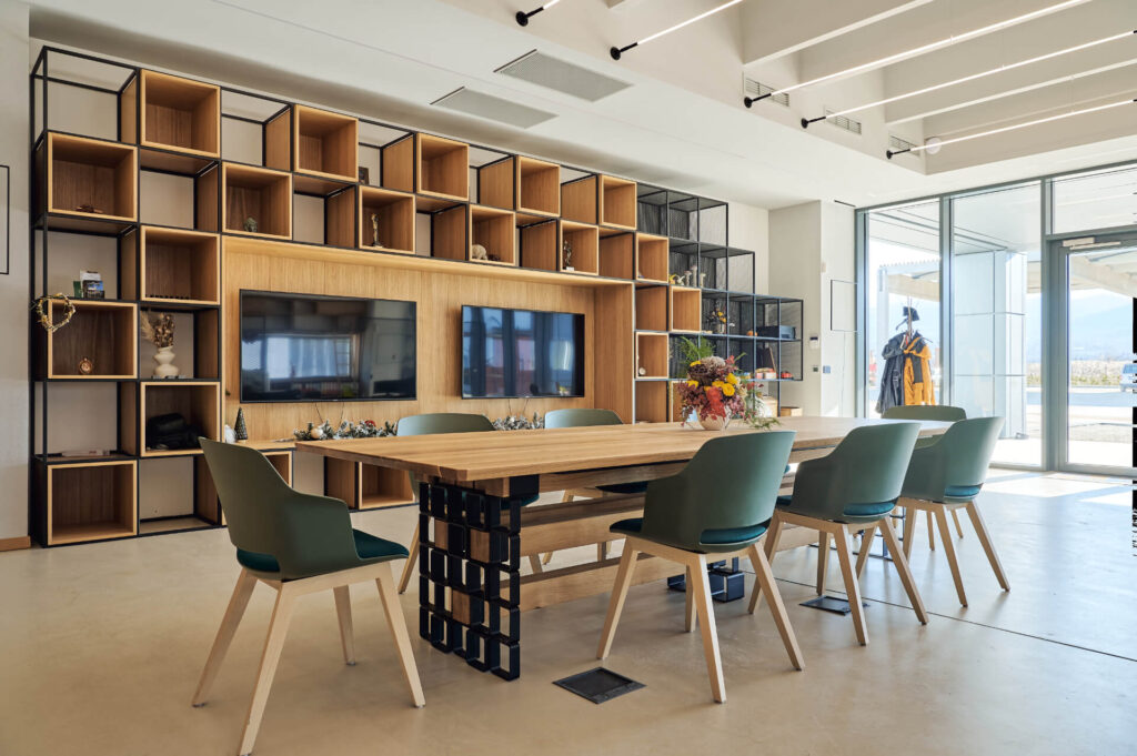 Модерна заседателна зала от Интериорен дизайн Studio28a с дървена маса, зелени столове, рафтове и големи прозорци.