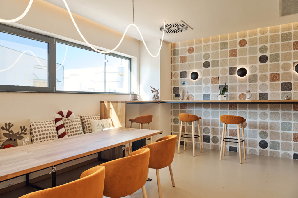 Модерна кухненска зона с оранжеви столове, дървена маса и естествена светлина. Интериорен дизайн Студио28а стил.