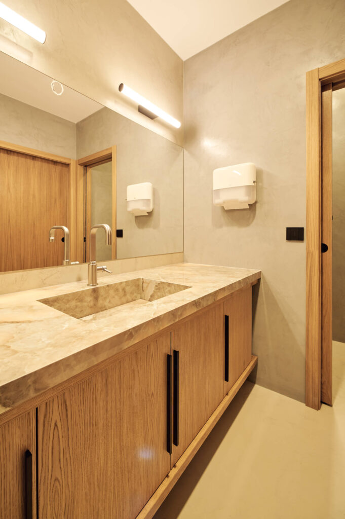 Модерна тоалетна с голямо огледало, мраморен плот и дървени шкафове от Интериорен дизайн Studio28a.