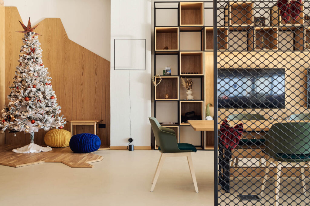 Модерна дневна от Интериорен дизайн Studio28a с коледна елха, рафтове, бюро, столове и мрежест разделител.