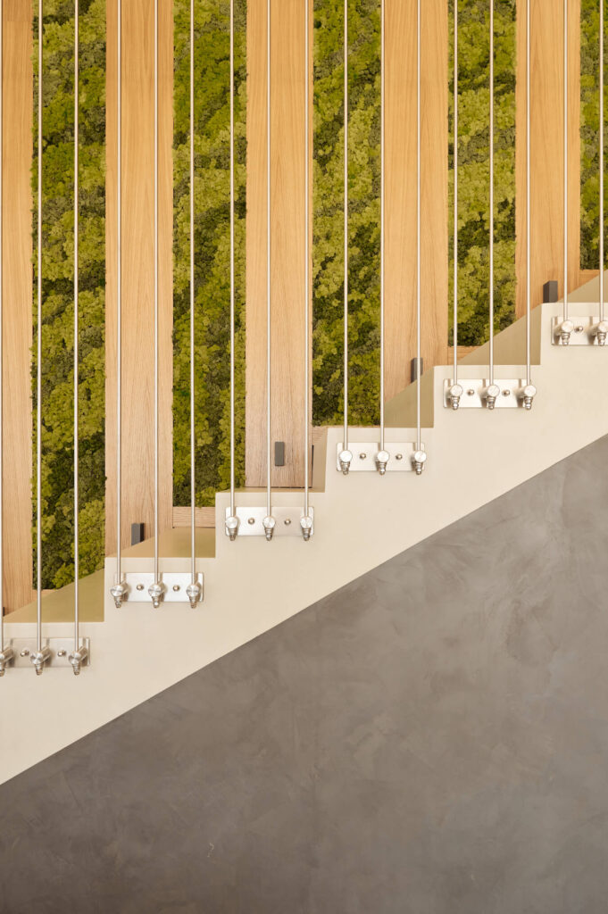 Модерно стълбище с дървени ламели, метални въжета и зелена стена от мъх от Интериорен дизайн Studio28a.