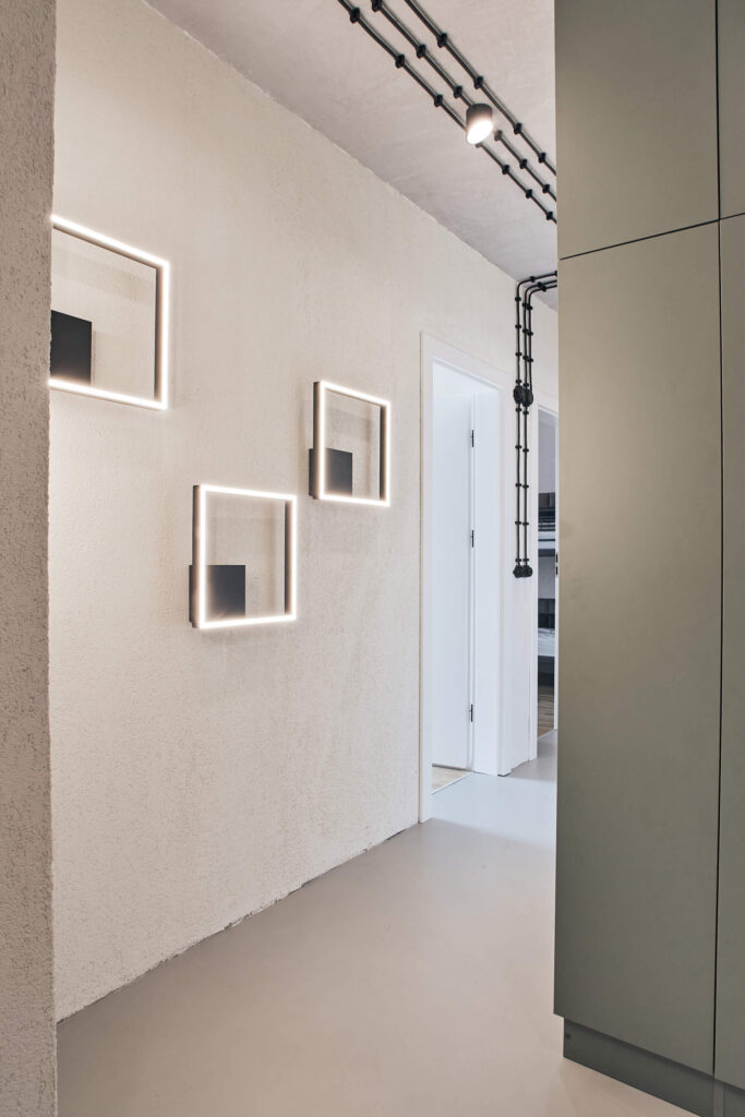 Бяла стена с лампи и врата, оформена от Интериорен дизайн Studio28a.