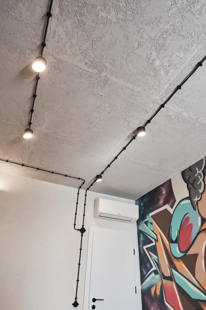 Таван с открито осветление от Интериорен дизайн Studio28a, бели текстурирани стени и стенопис с графити в близост до вратата.