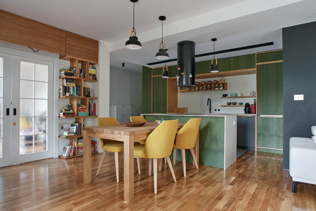 Модерна кухня и трапезария от Интериорен дизайн Studio28a, със зелени шкафове, дървена маса, жълти столове и рафт за книги.