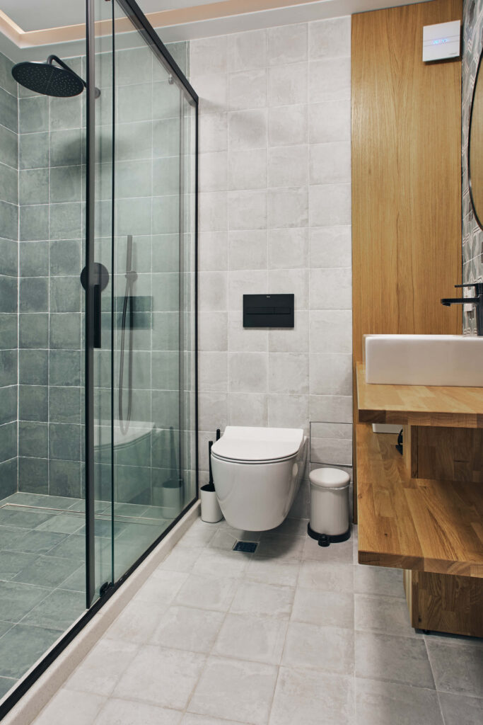 Модерна баня от Интериорен дизайн Studio28a със стъклен душ, стенна тоалетна и дървена тоалетна.
