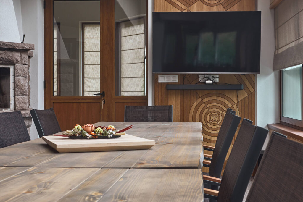 Дървена трапезна маса с флорална украса е заобиколена от столове, изработени от Интериорен дизайн Studio28a.