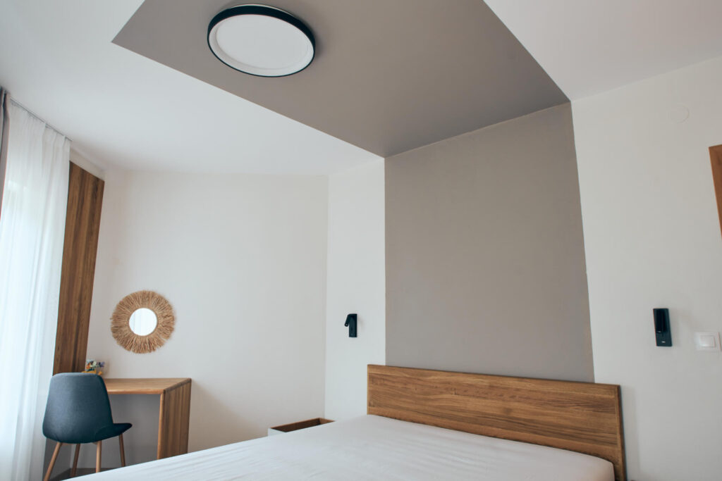 Минималистична спалня от Интериорен дизайн Studio28a с дървена табла, малко бюро, стол и неутрална палитра.