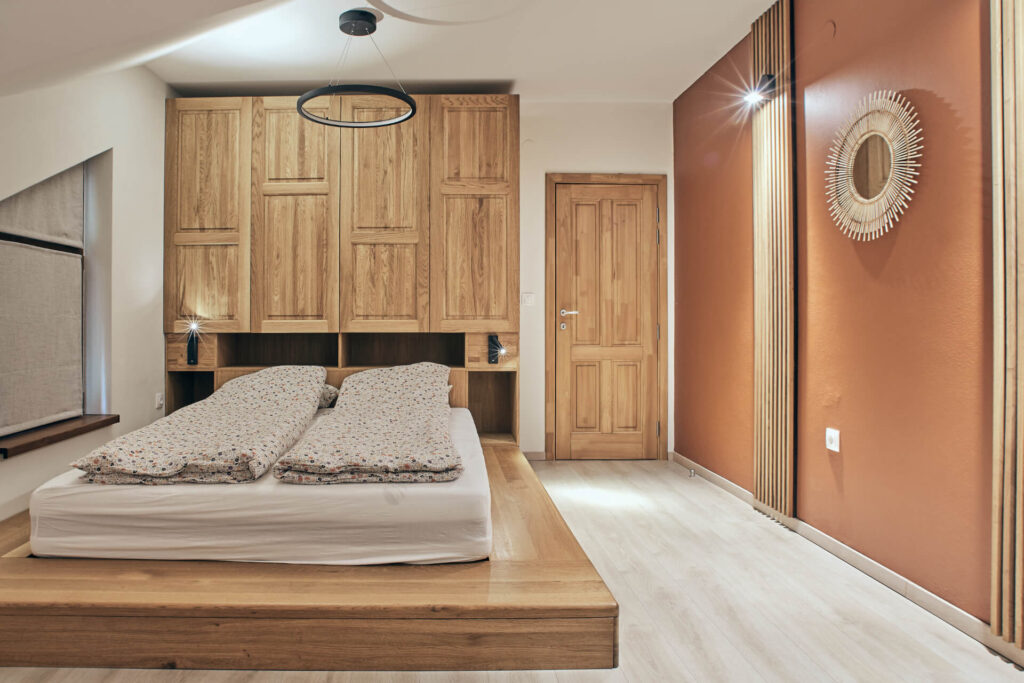 Минималистична спалня от Интериорен дизайн Studio28a с легло с дървена платформа, вградени шкафове и оранжева акцентна стена.