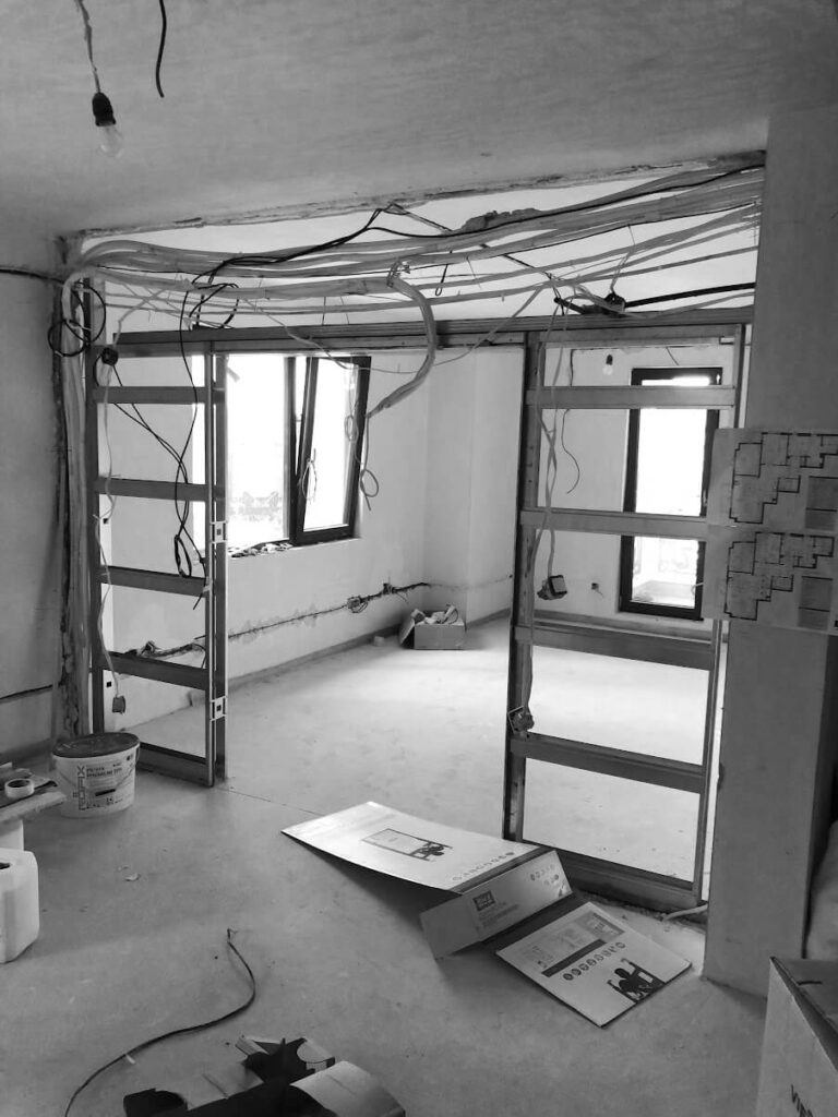 Незавършено помещение в процес на ремонт от Интериорен дизайн Studio28a с открити кабели, инструменти и отворена рамка.