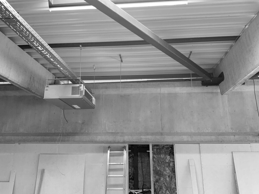 Индустриален таван с открити греди и тръбопроводи от Интериорен дизайн Studio28a; стълба под отворен панел за достъп.