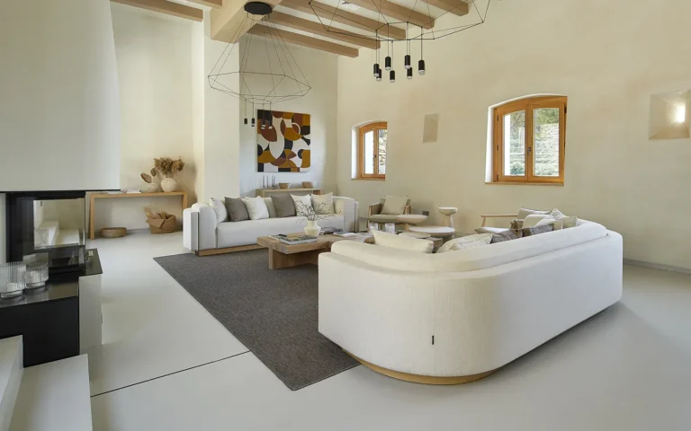 Модерната всекидневна на Интериорен дизайн Studio28a включва два бели дивана, сив килим и големи прозорци.